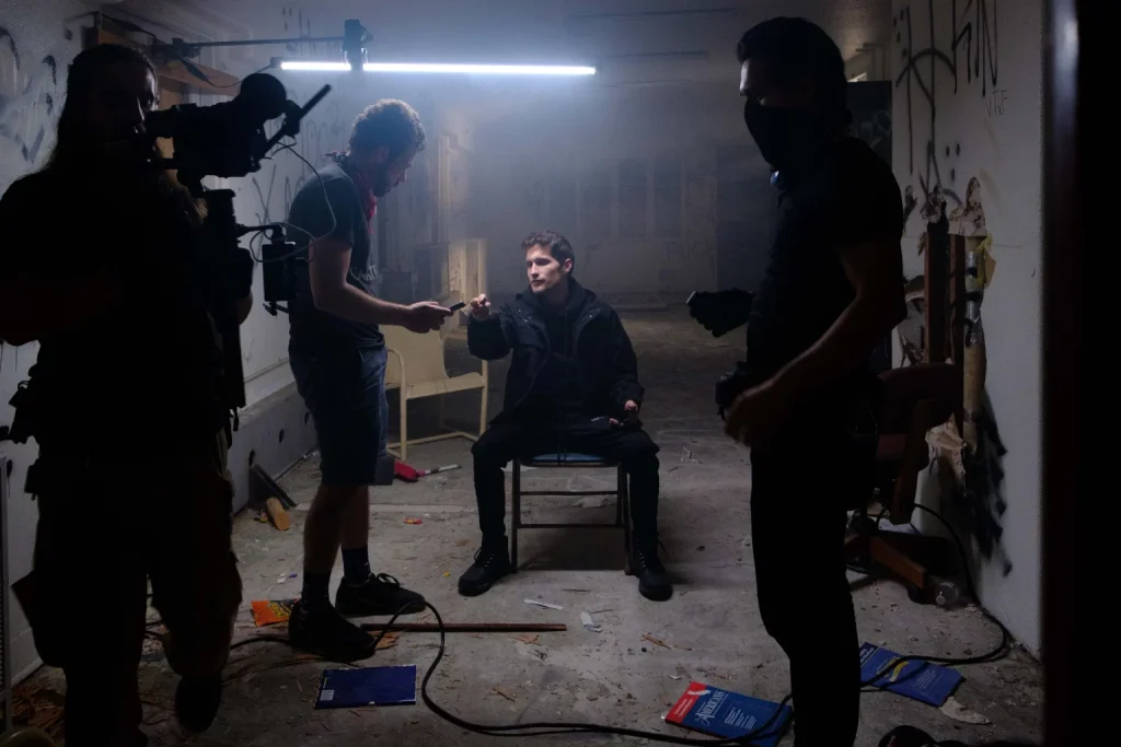 A crew and an actor between takes in a dim, smoky room
