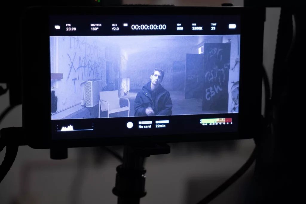 A camera monitor framing an actor in a graffiti-covered room