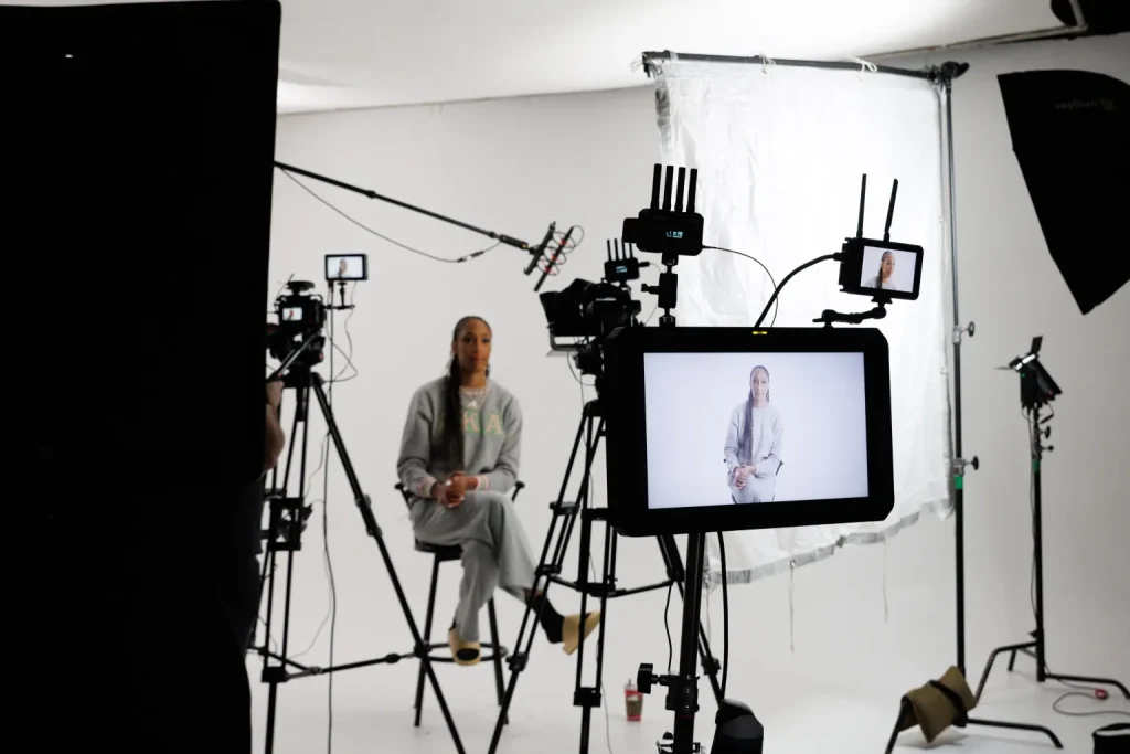 A studio set with lights, a camera and a monitor showing the take