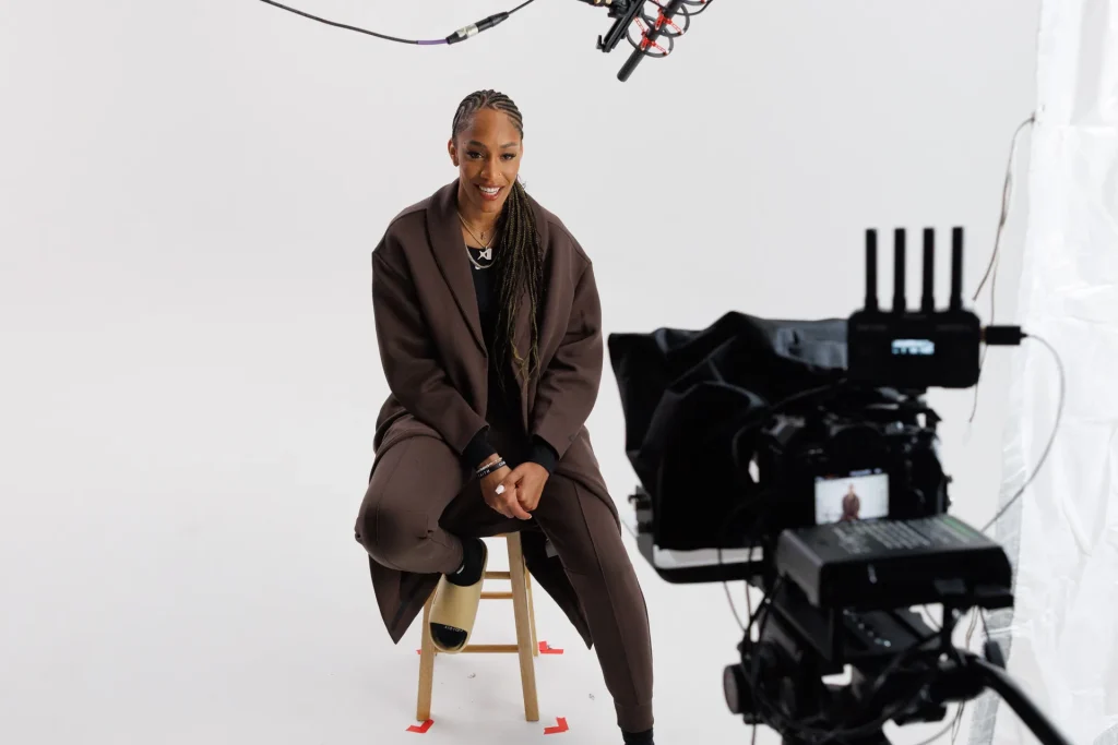 A performer seated on a stool in front of a camera rig