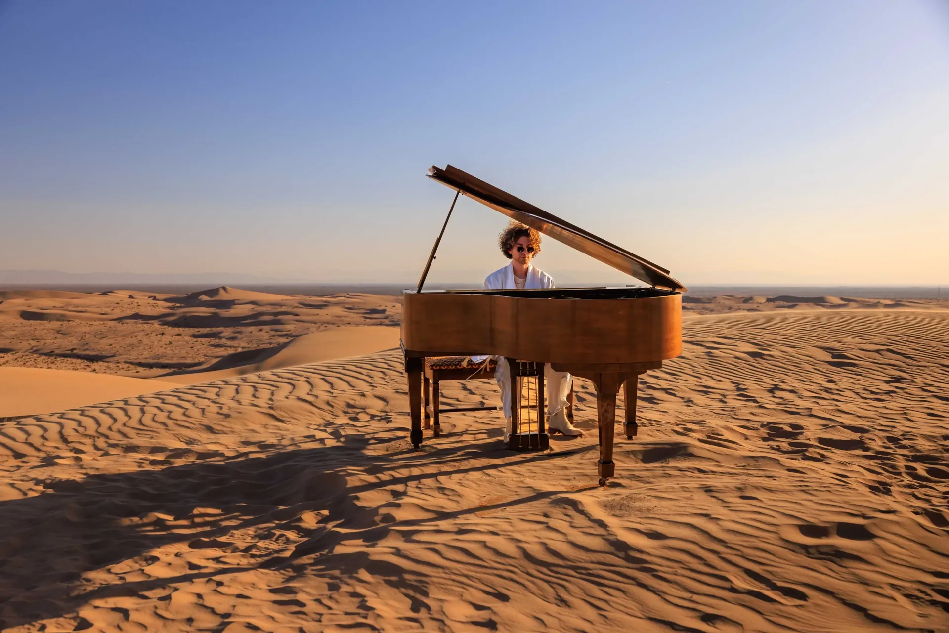 A grand piano in the desert dunes, on a music video shoot